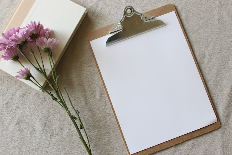 image showing a blank page and purple flowers beside it.